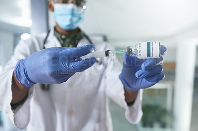 Buy stock photo Shot of a young doctor extracting liquid with a syringe from a vial in an office