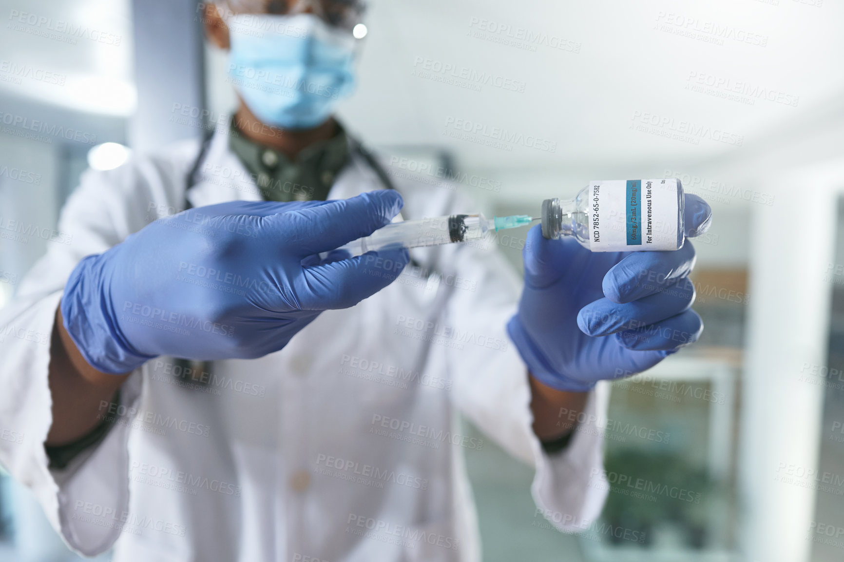 Buy stock photo Shot of a young doctor extracting liquid with a syringe from a vial in an office