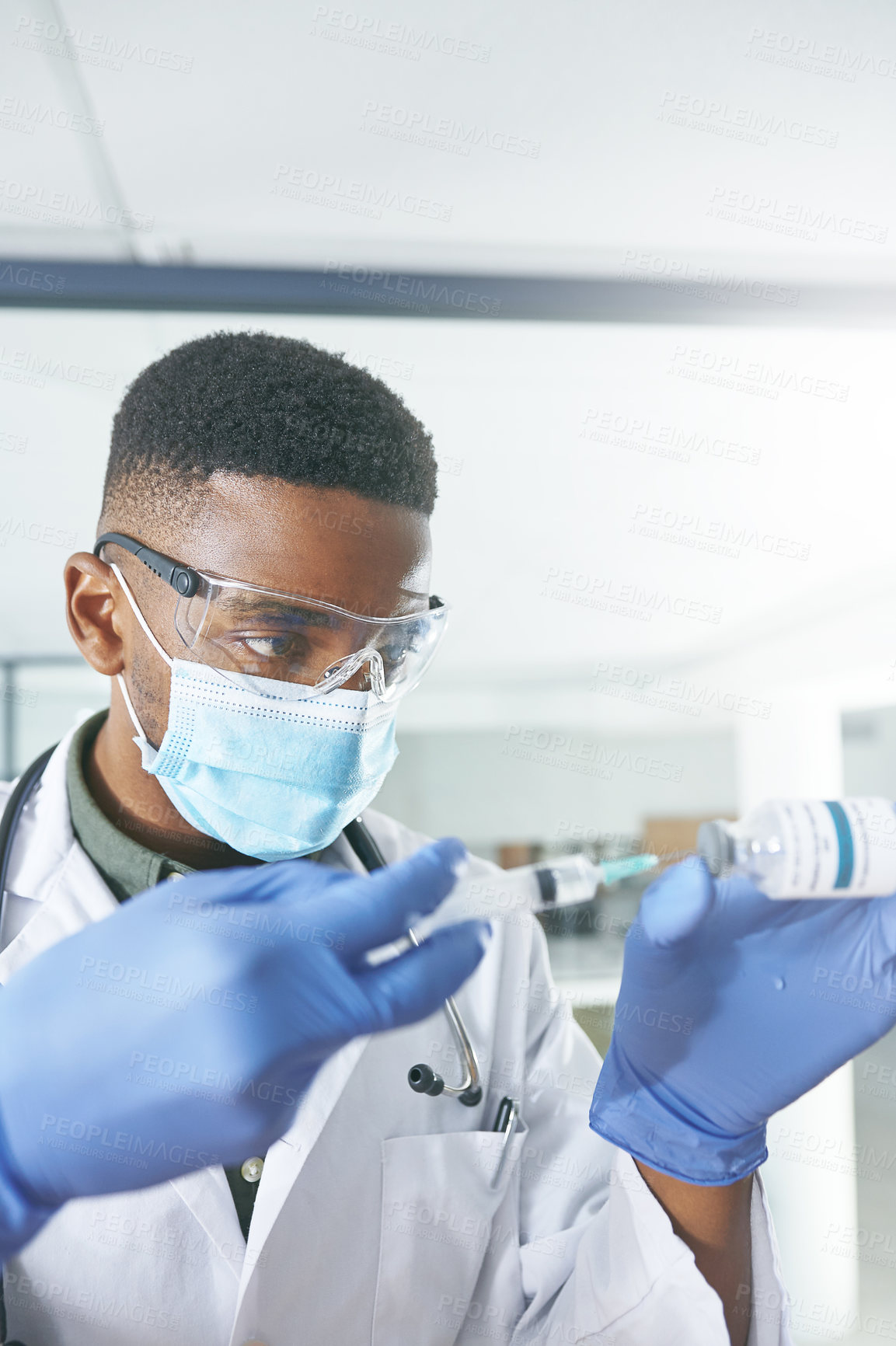 Buy stock photo Shot of an young doctor extracting liquid with a syringe from a vial in an office