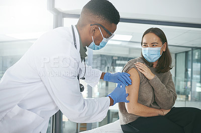 Buy stock photo Shot of a young doctor giving a patient an injection in an office