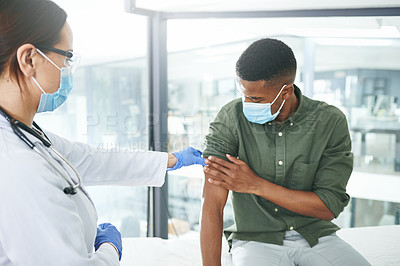 Buy stock photo Shot of a young doctor preparing a patient for an injection in an office