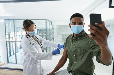 Buy stock photo Shot of a young doctor giving a patient an injection while he takes a selfie in an office