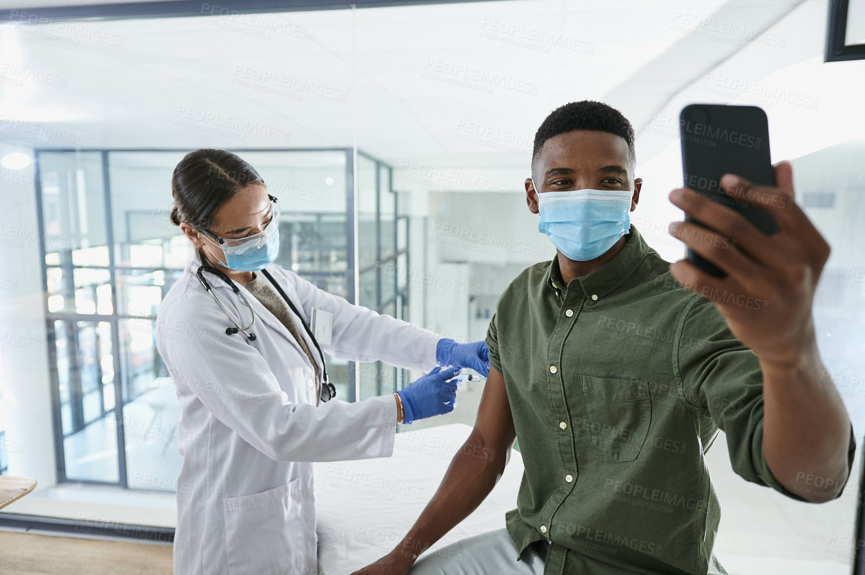 Buy stock photo Shot of a young doctor giving a patient an injection while he takes a selfie in an office