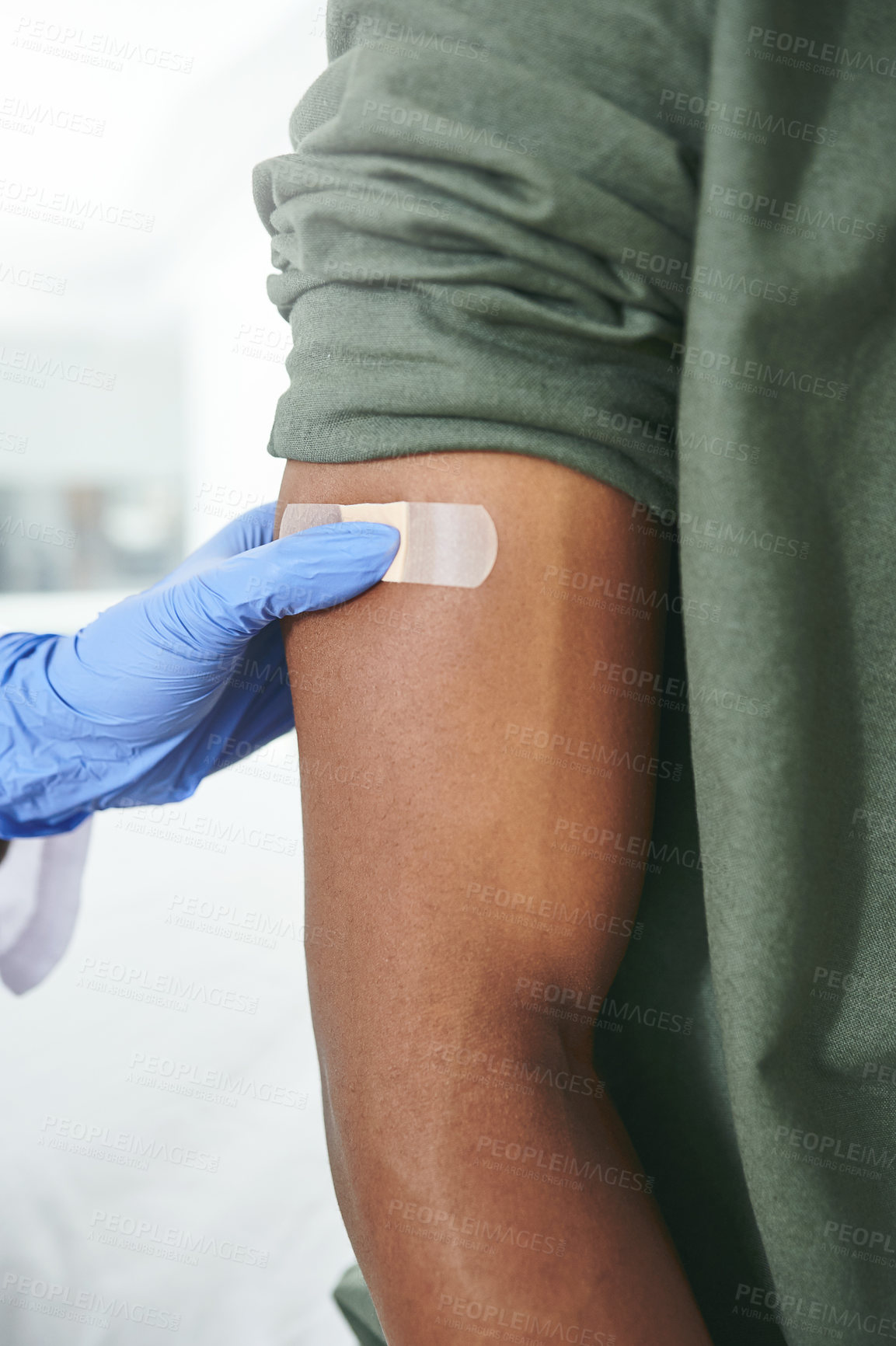 Buy stock photo Shot of an unrecognizable doctor applying a band-aid to a patient's arm