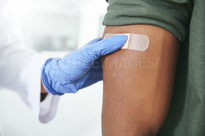 Buy stock photo Shot of an unrecognizable doctor applying a band-aid to a patient's arm