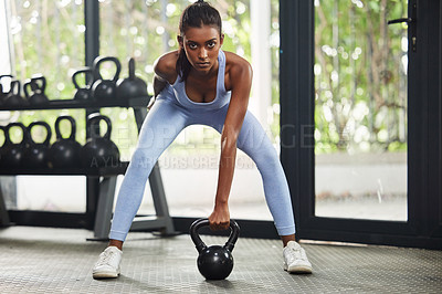 Buy stock photo Shot of a young woman working out with a kettle bell at the gym