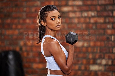 Buy stock photo Shot of a sporty young woman working out with dumbbells at the gym