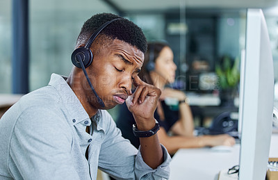 Buy stock photo Shot of a young call centre agent looking tired in an office