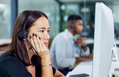 Buy stock photo Shot of a young call centre agent looking confused while using a desktop pc in an office
