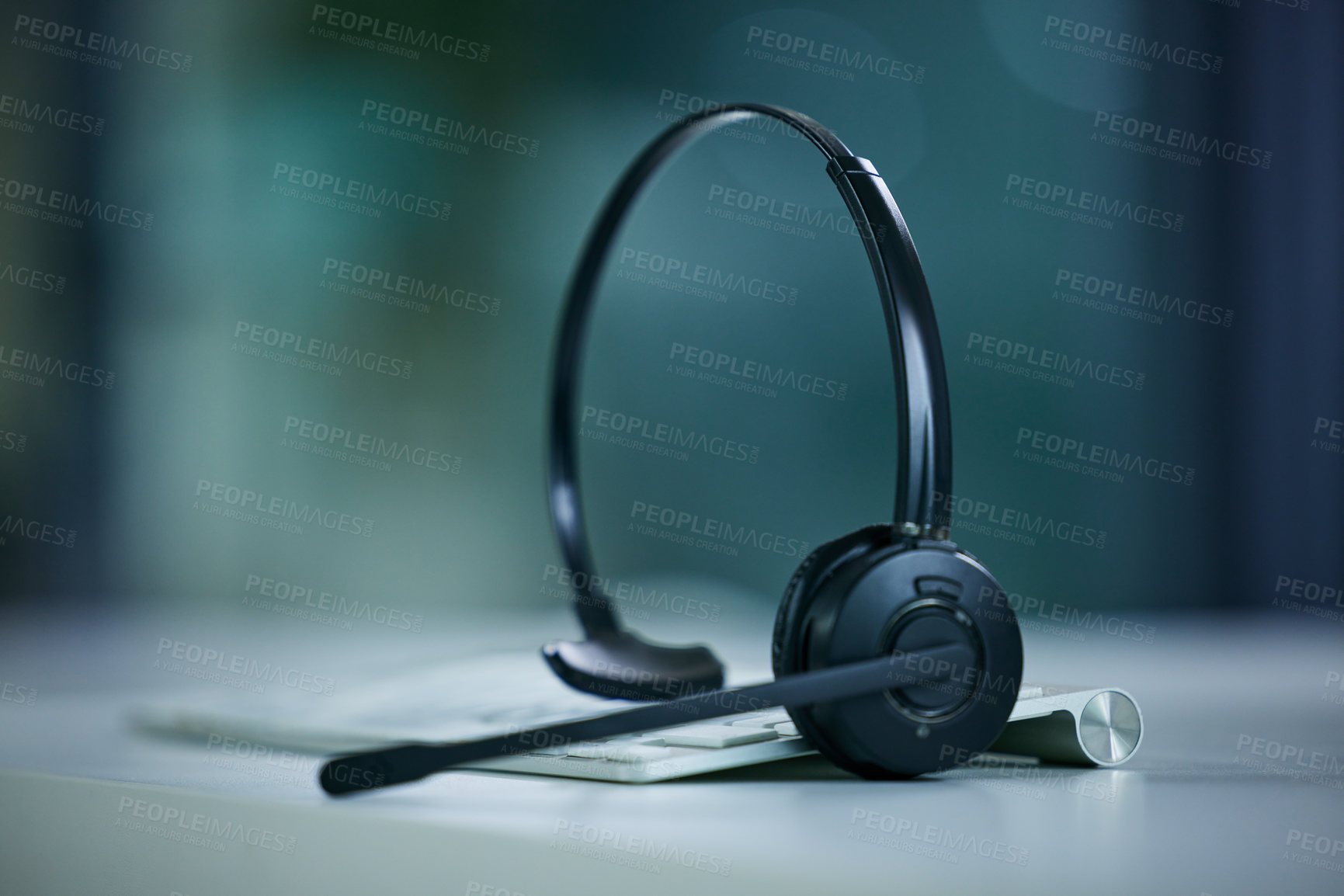 Buy stock photo Closeup shot of a headset lying on a keyboard in an office