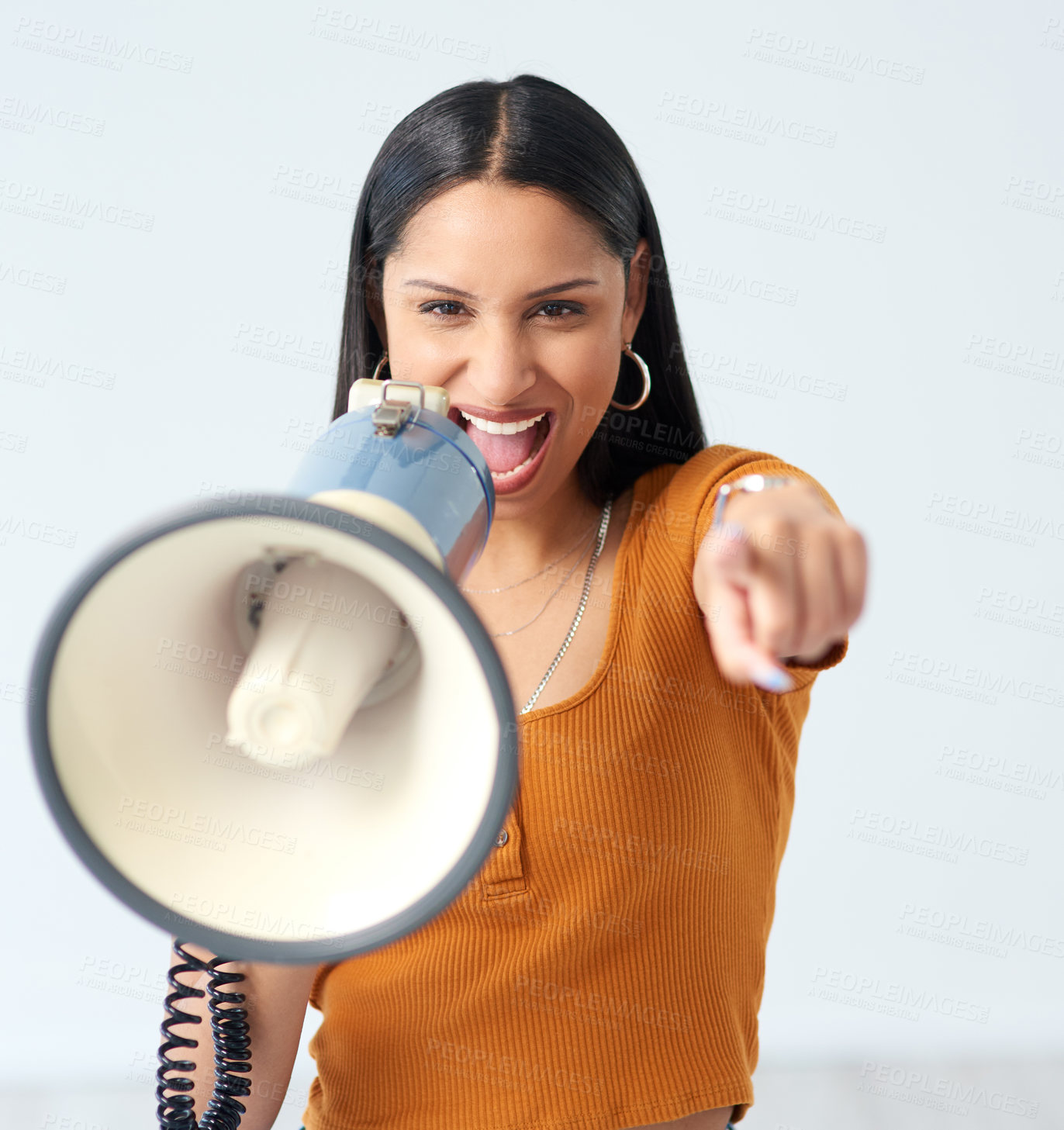 Buy stock photo Cropped portrait of an attractive young woman shouting into a megaphone and pointing at the camera in studio