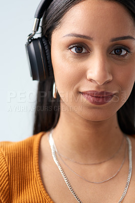 Buy stock photo Cropped portrait of an attractive young woman wearing headphones in studio against a grey background