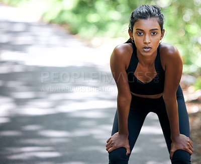 Buy stock photo Shot of an attractive young woman taking a moment to catch her breath during her run outdoors