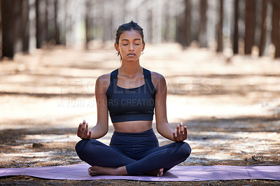 Buy stock photo Shot of an attractive young woman sitting alone on a yoga mat outdoors and meditating
