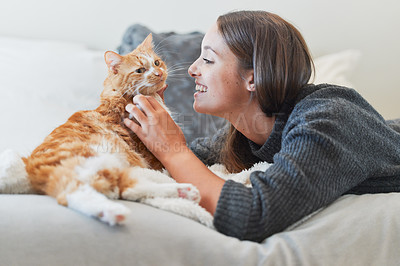 Buy stock photo Shot of a young woman petting her cat at home