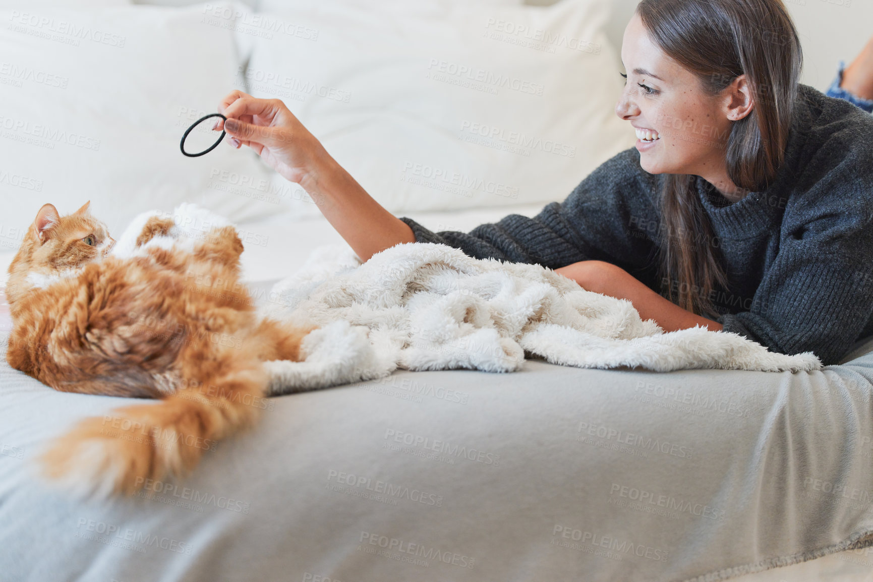 Buy stock photo Love, happy and woman playing with cat in bedroom of home for bonding or fun as pet owner. Bed, smile and toys with person teasing adorable kitten in apartment for morning or winter relaxation