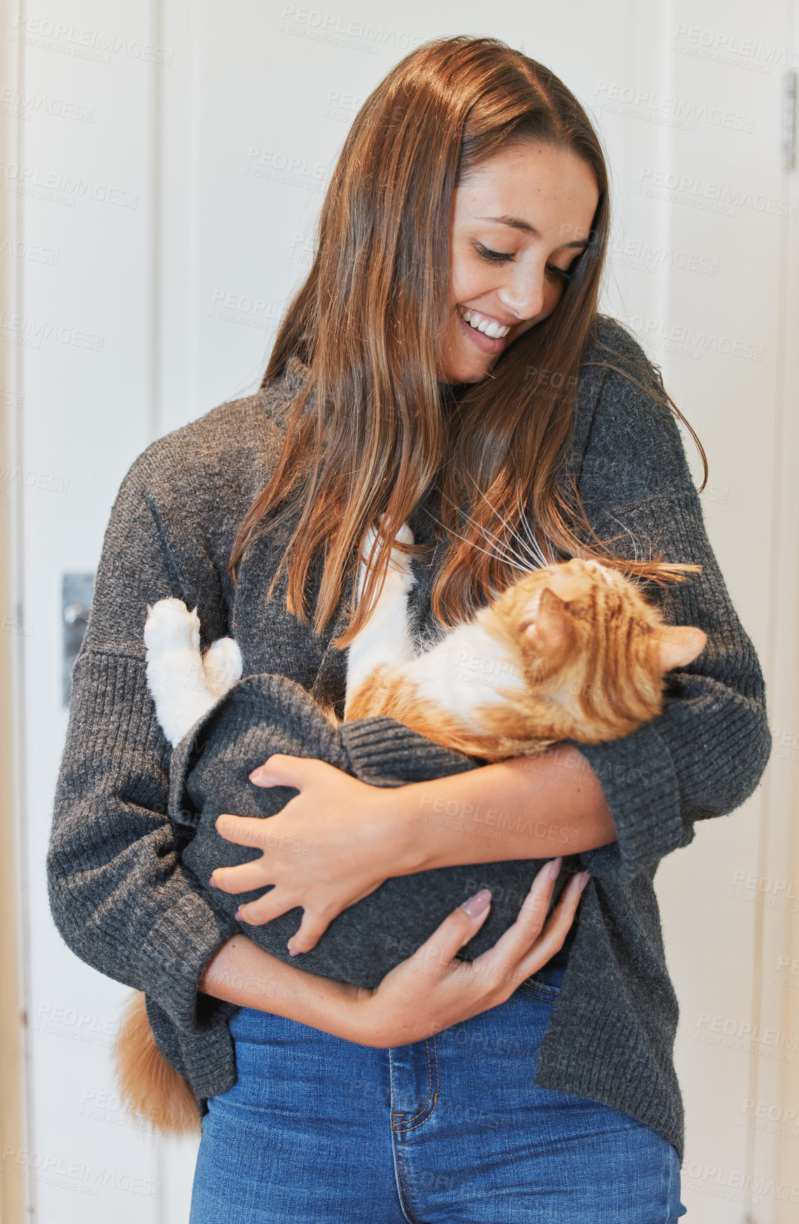 Buy stock photo Shot of a young woman carrying her cat at home