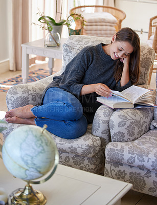 Buy stock photo Shot of a young woman reading a book at home