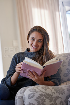 Buy stock photo Portrait of a young woman reading a book at home