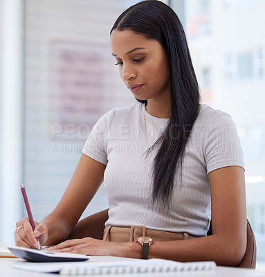 Buy stock photo Shot of an attractive young businesswoman sitting alone in the office and writing in her notebook