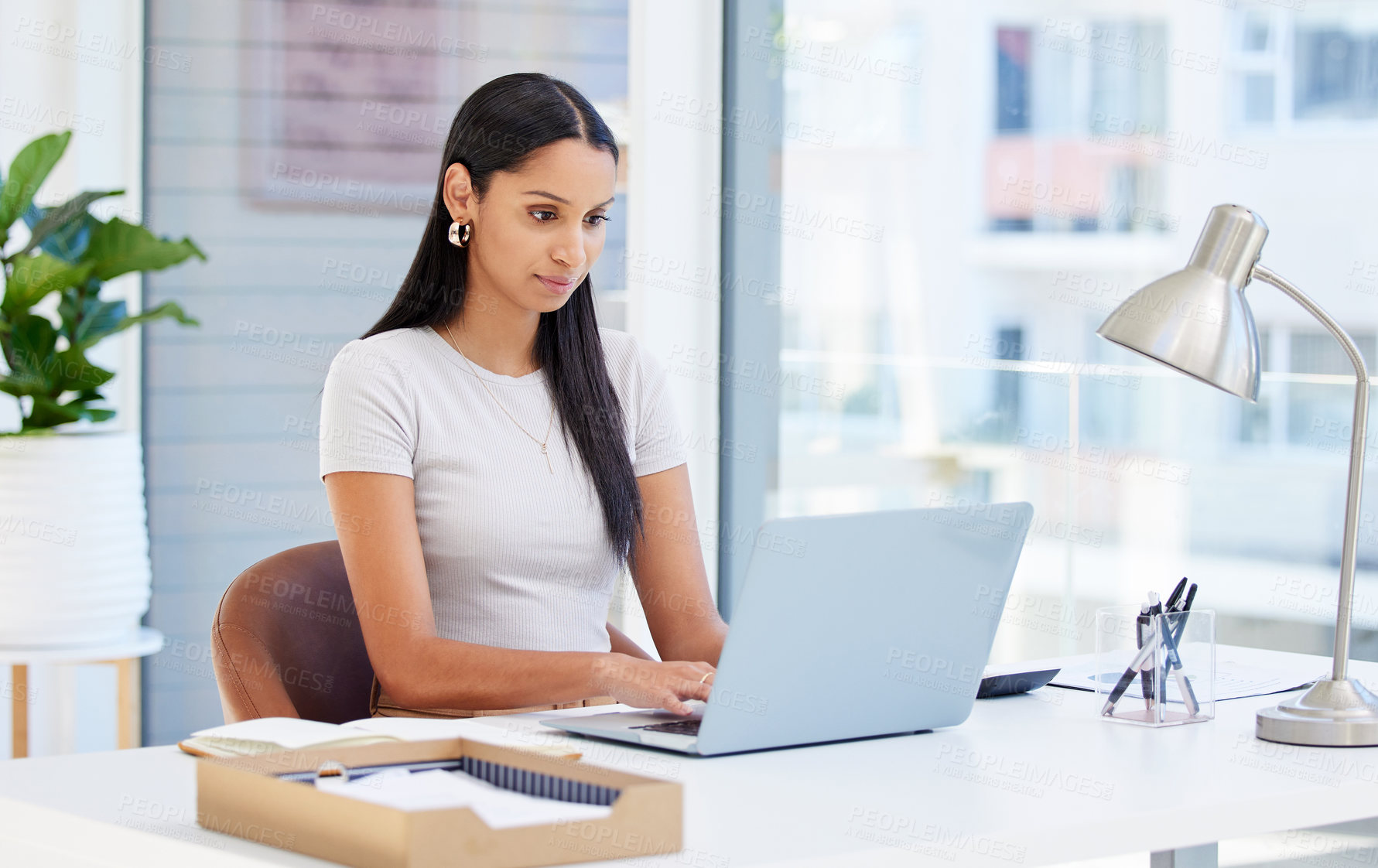 Buy stock photo Shot of a young businesswoman using her laptop at work