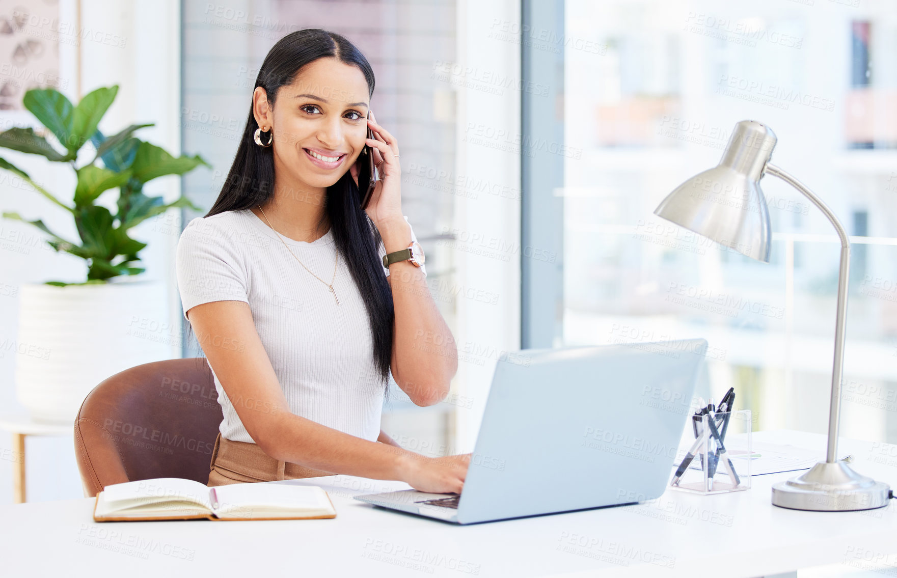 Buy stock photo Shot of a young businesswoman using her smartphone at work