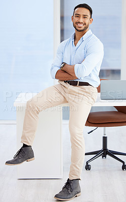 Buy stock photo Shot of a young businessman sitting on a desk at work
