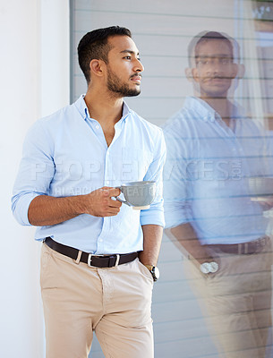 Buy stock photo Shot of a young businessman drinking a cup of coffee at work