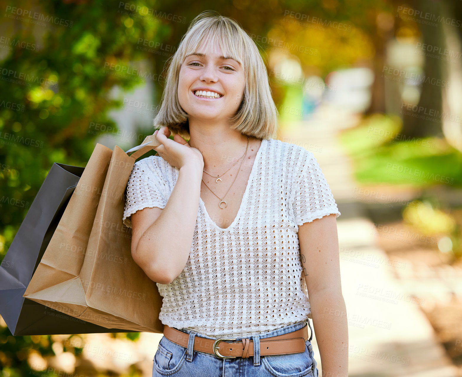 Buy stock photo Shot of a young woman walking outside with shopping bags