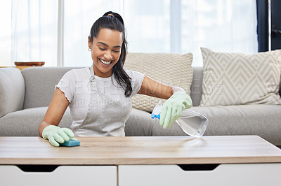 Buy stock photo Shot of an attractive young woman using a sponge and spray bottle to clean the surfaces at home