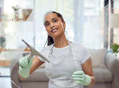 Buy stock photo Shot of an attractive young woman standing alone at home and cleaning her windows