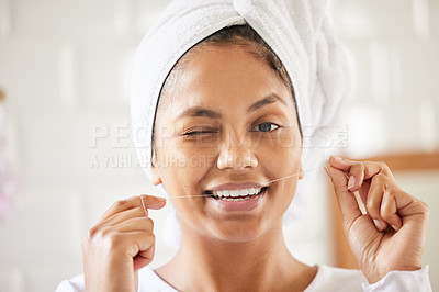 Buy stock photo Shot of an attractive young woman flossing her teeth in the bathroom