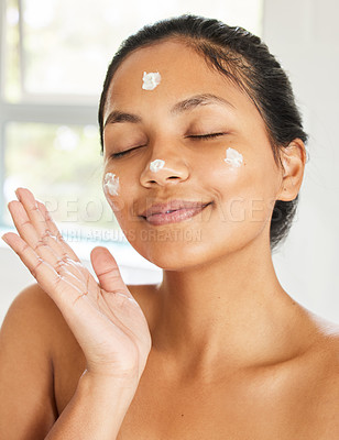 Buy stock photo Shot of young woman using with facial moisturiser at home