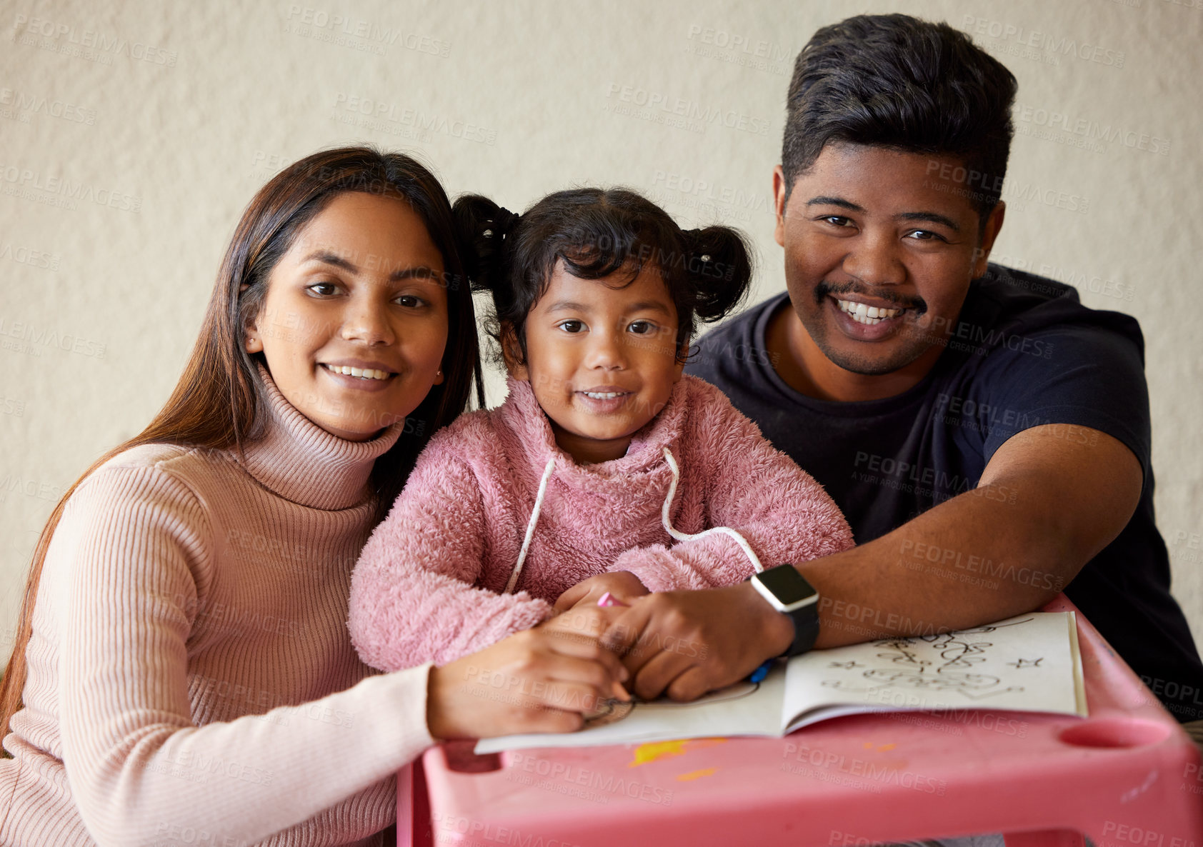 Buy stock photo Shot of a young parents helping their little girl complete a colouring book