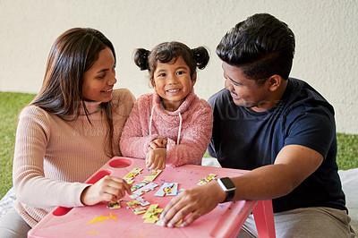 Buy stock photo Shot of young parents helping their daughter build a puzzle