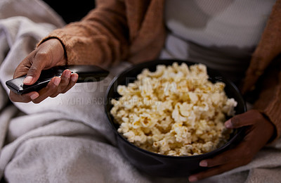 Buy stock photo High angle shot of an unrecognizable woman eating popcorn while watching tv at home