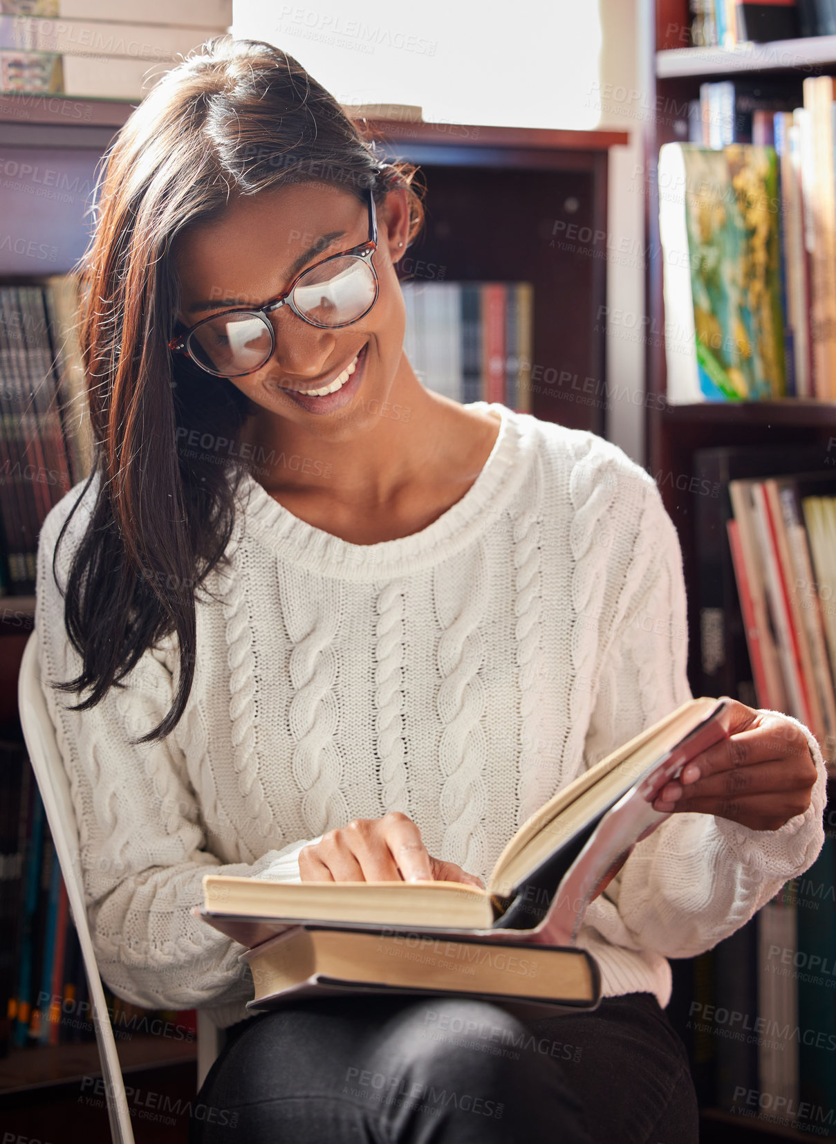 Buy stock photo Shot of a young woman reading a book in a library