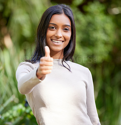 Buy stock photo Shot of a beautiful young woman showing thumbs up while standing outside