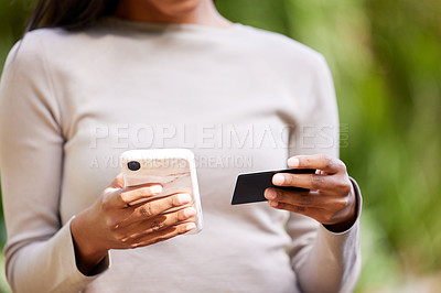 Buy stock photo Cropped shot of an unrecognizable woman holding a cellphone and a credit card while standing outside