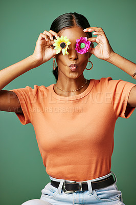 Buy stock photo Shot of a young woman covering her eyes with two flowers shot against a studio background