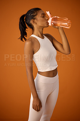 Buy stock photo Healthy, studio or Indian woman drinking water for fitness, hydration or workout break on orange background. Tired girl, training or thirsty athlete with fresh h2o liquid drink for exercise or detox