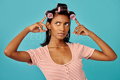 Buy stock photo Shot of a young woman with rollers in her hair shot against a studio background