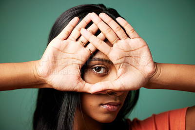 Buy stock photo Shot of a young woman covering her face with her hand shot against a studio background