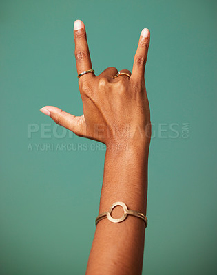 Buy stock photo Rock and roll hand sign by a studio for party, cool or wild greeting with rings and bracelet jewelry. Emoji, punk and woman rebel or rocker gesture with fingers isolated by a dark green background.