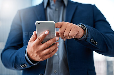 Buy stock photo Cropped shot of an unrecognizable businessman standing alone in the office and using his cellphone