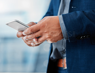 Buy stock photo Cropped shot of an unrecognizable businessman standing alone in the office and using his cellphone
