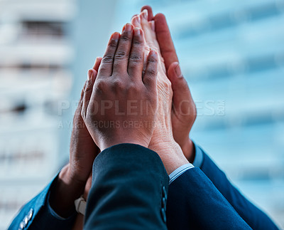 Buy stock photo Cropped shot of a group of unrecognizable businessmen giving each other a high five against an urban background