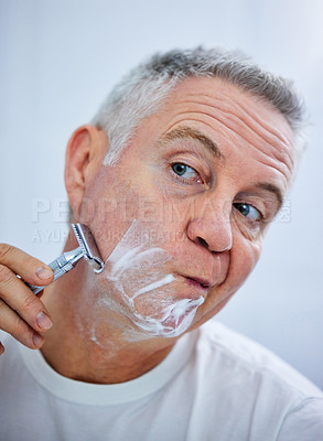 Buy stock photo Shot of a mature man shaving his face in a bathroom at home