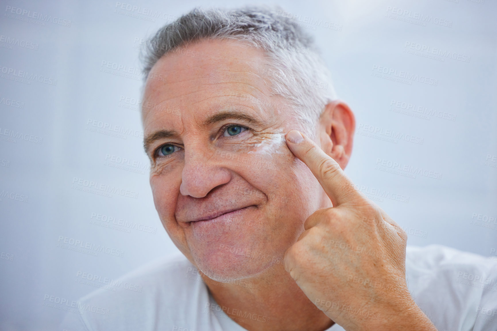 Buy stock photo Shot of a mature man applying cream to his face in a bathroom at home