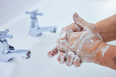 Buy stock photo Shot of an unrecognizable man washing his hands with soap at home